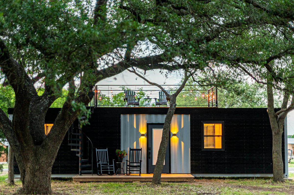 A small dark-clad backyard dwelling under trees